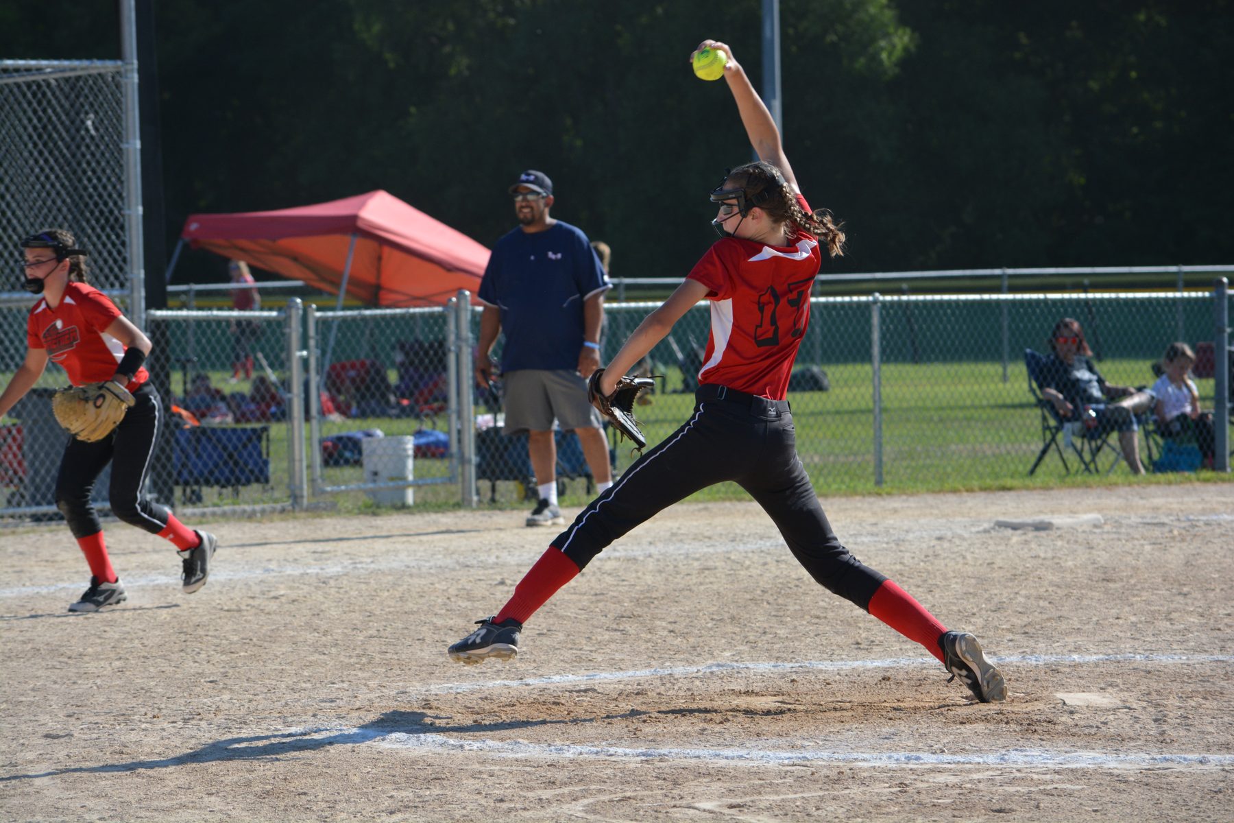 Teagan pitching as a youth player in a red #17 jersey